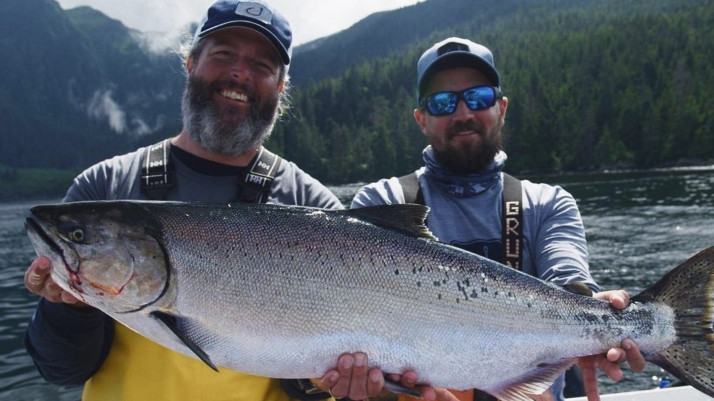 Two men holding a large salmon.