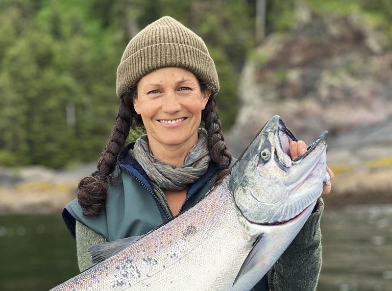 Smiling woman with braided hair holding a large fish